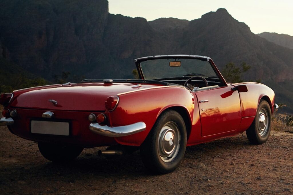 A vintage red card parked on a dirt road
