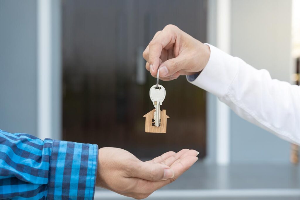 A person handing a house key to someone else