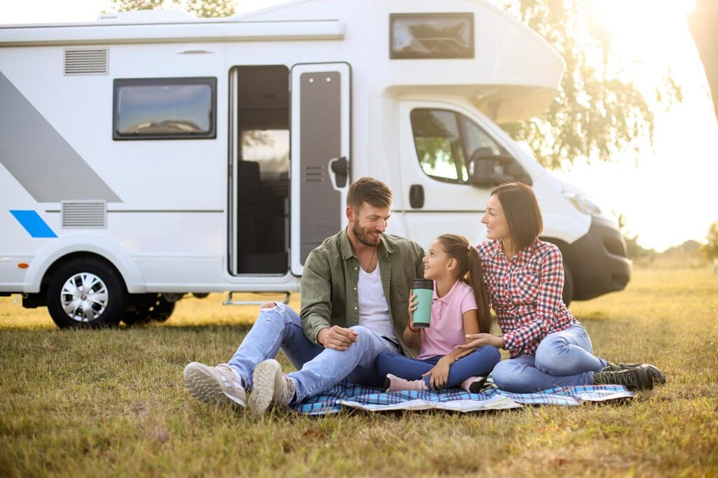 A family sitting in front of their RV