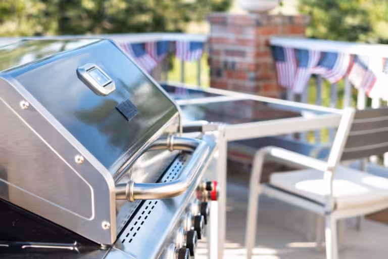 Stainless steel gas grill on a deck beside a patio table, illustrating grill rules and condo insurance in Ohio