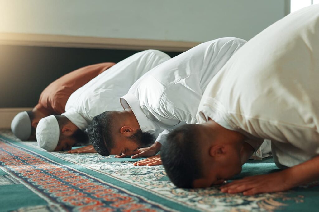 Four men with their head on the ground praying in a mosque